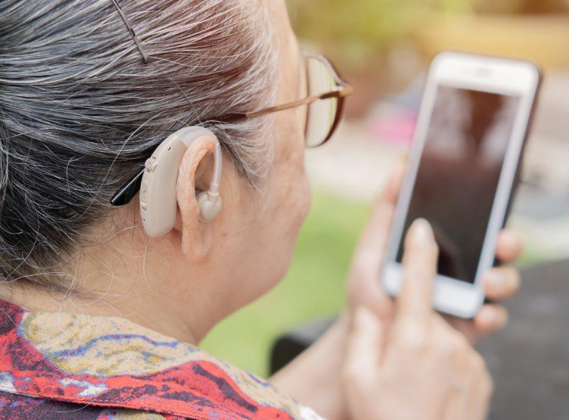 Woman with hearing aid looking at mobile phone